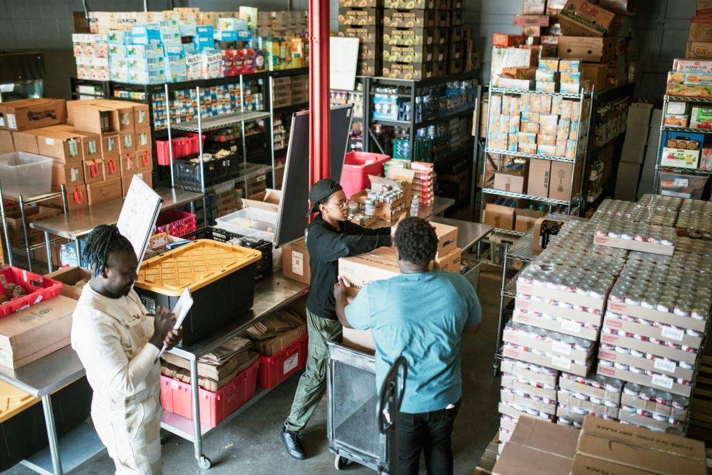 Inside a food bank filled with canned goods and packages, a group of volunteers process donations.
