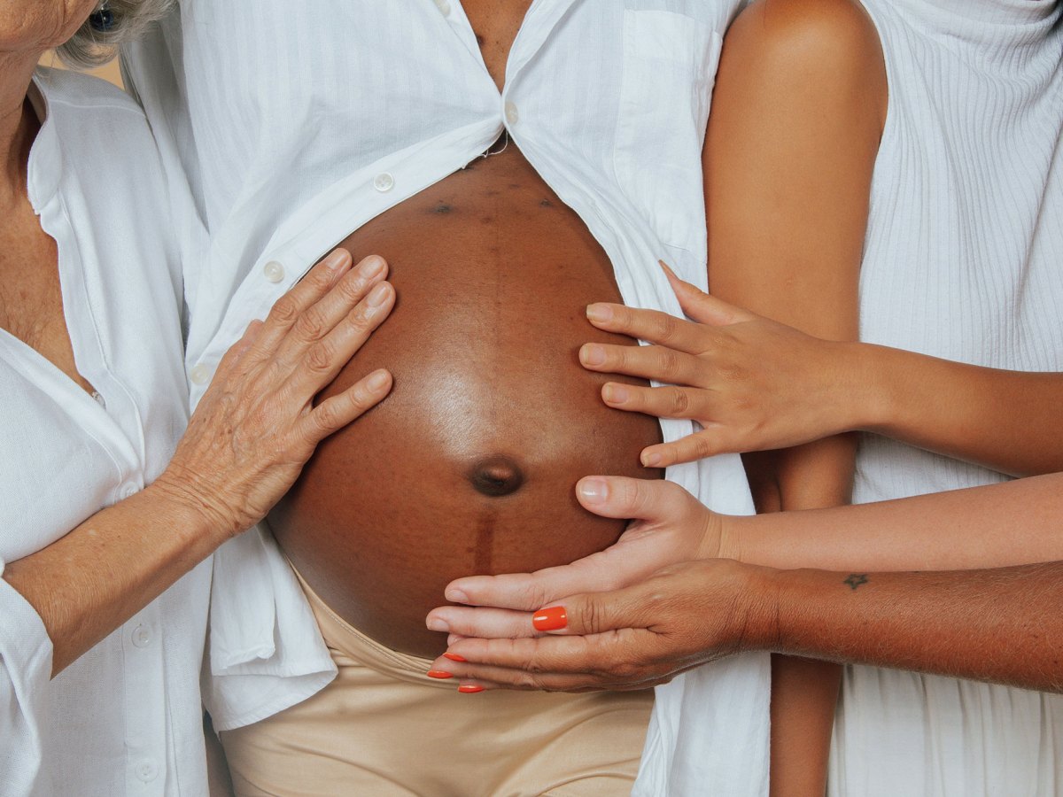 Hands touch a pregnant black woman's stomach