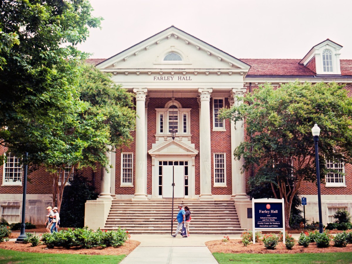 People walk past a campus building labeled Farley Hall