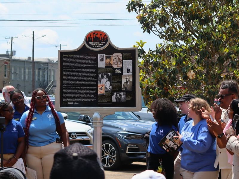 People look on at an unveiled marker and clap