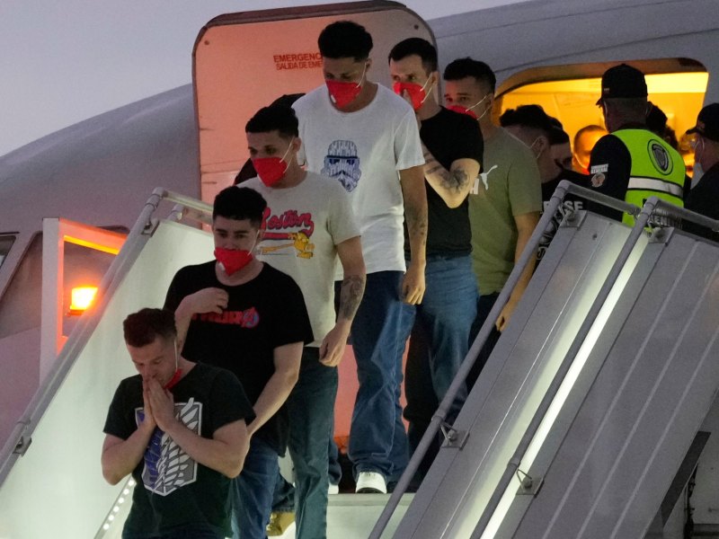 Men in red health masks unboard a plane