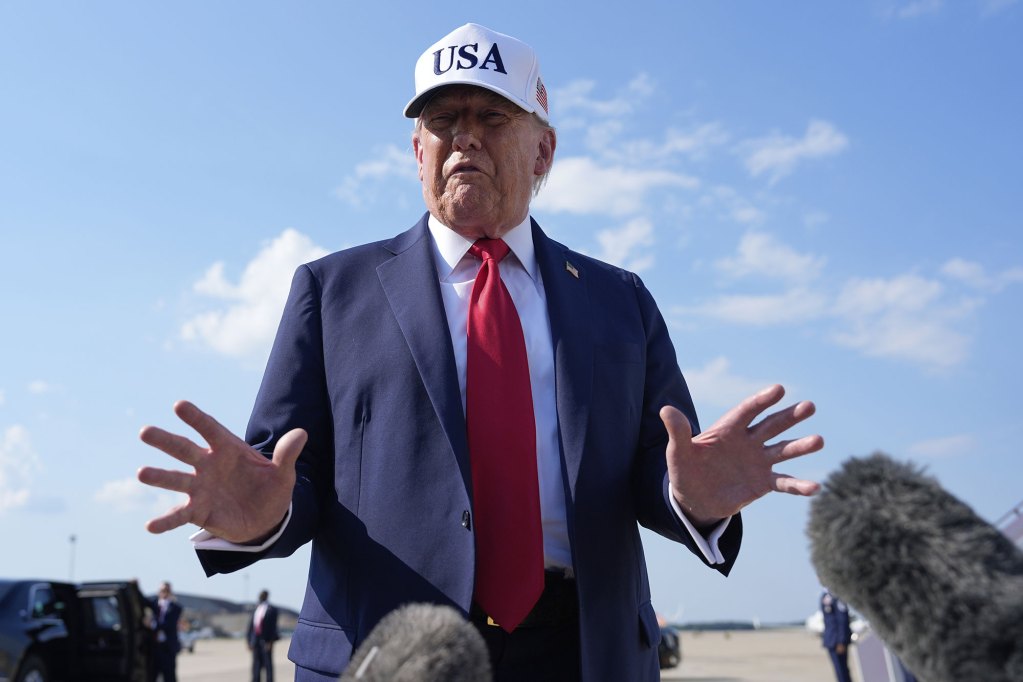Donald Trump wearing a white hat that reads USA