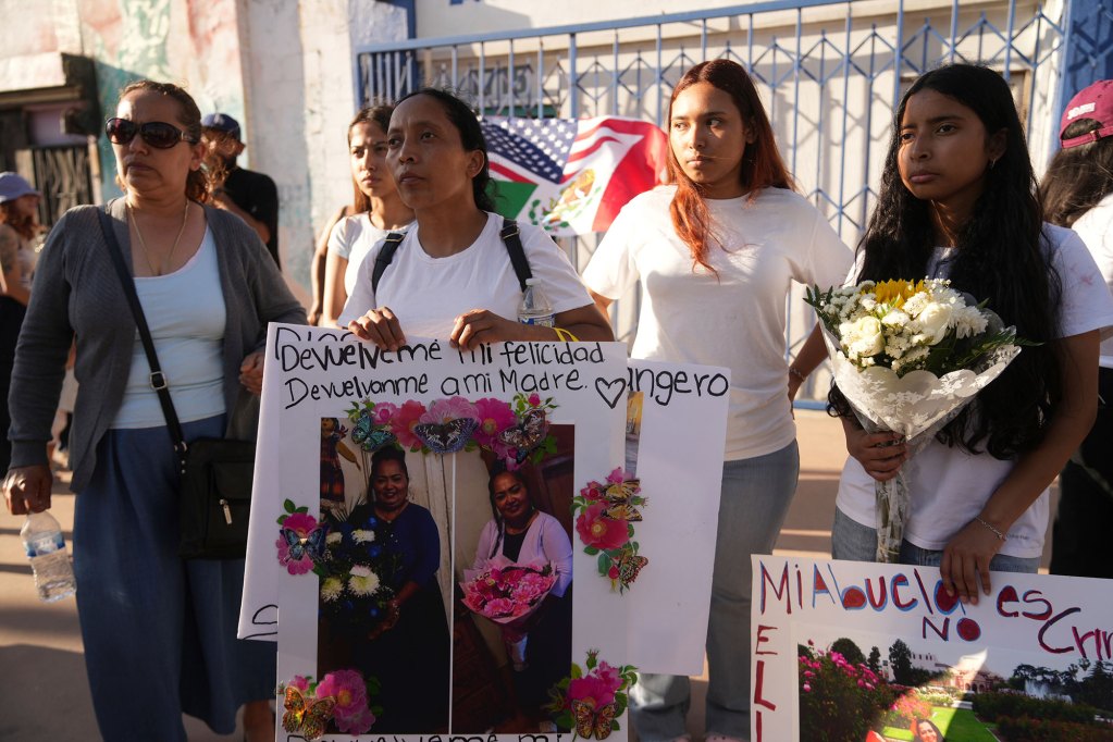 Family of a detained person hold up signs on the street