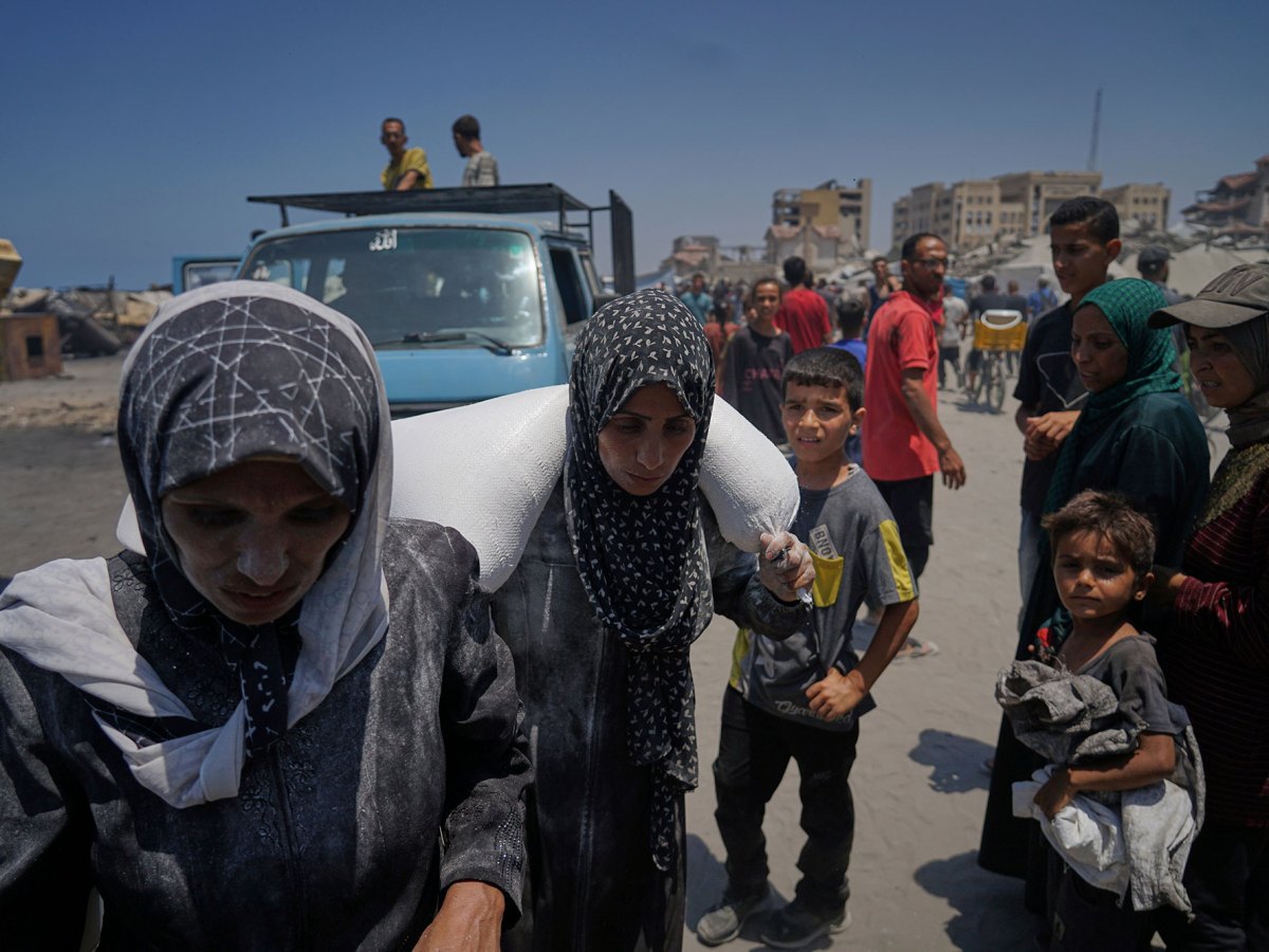 People carry a bag of flower from a humanitarian aid convoy
