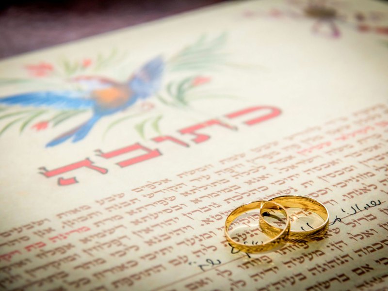 Two wedding rings on top of a marriage contract
