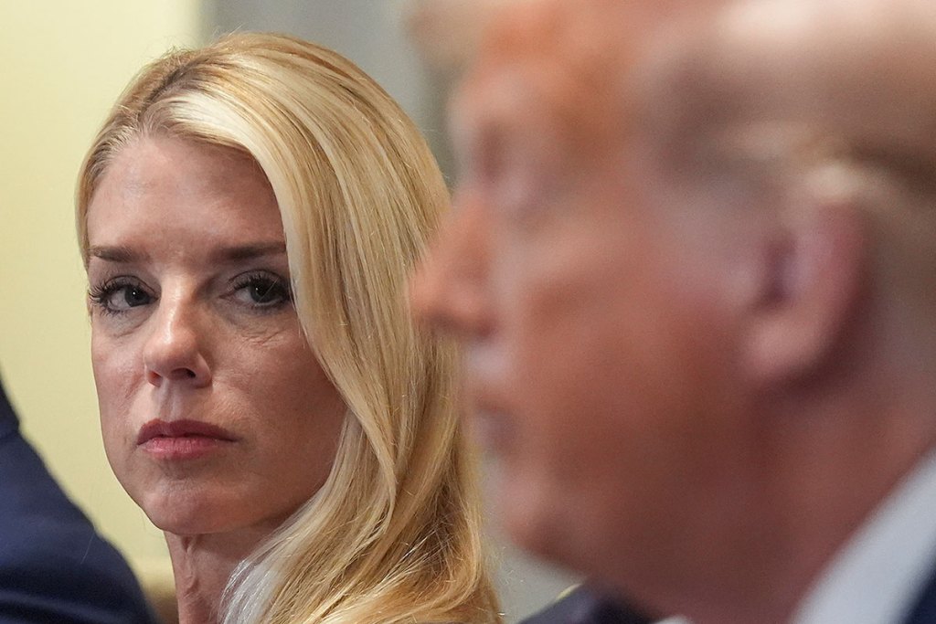 Pam Bondi, in focus, looks at Donald Trump