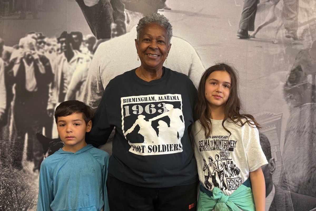 A woman poses with two children in front of a museum exhibit