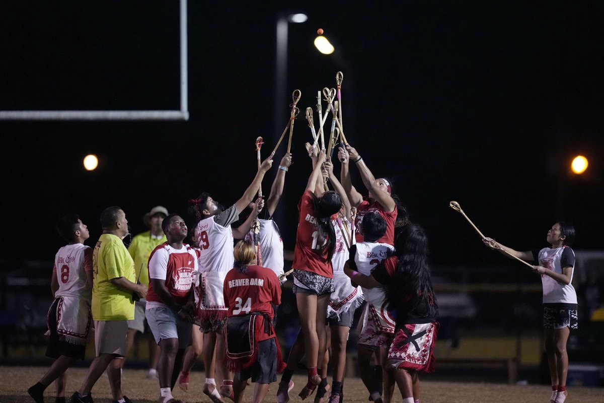 Two teams clash on the field in the attempt to catch the ball in a game of stickball