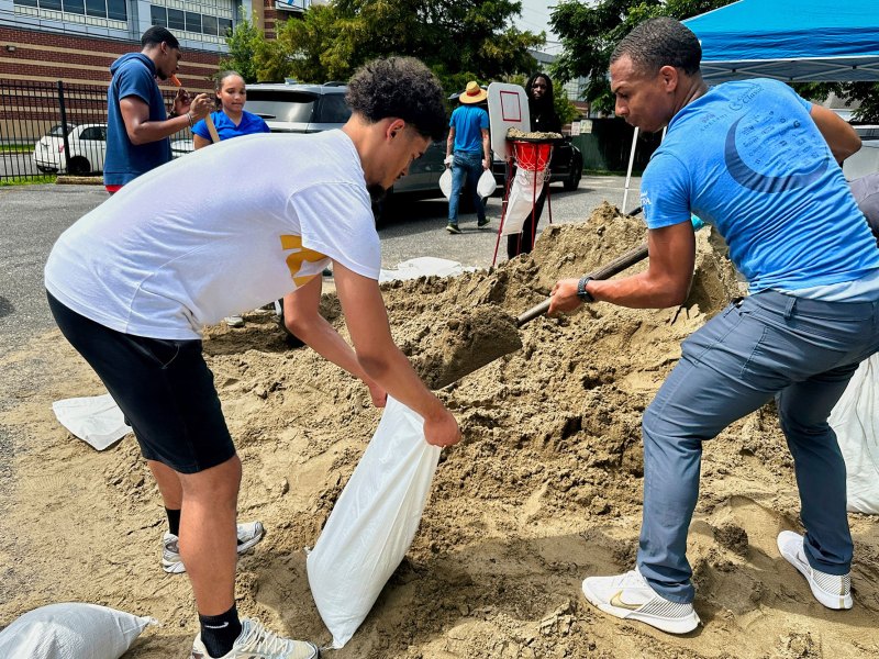 Two young men shoveling sand into bags