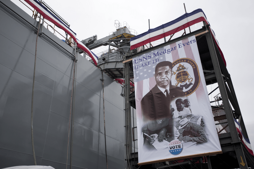 A sign with Medgar Ever's photo that reads USNS Medgar Evers