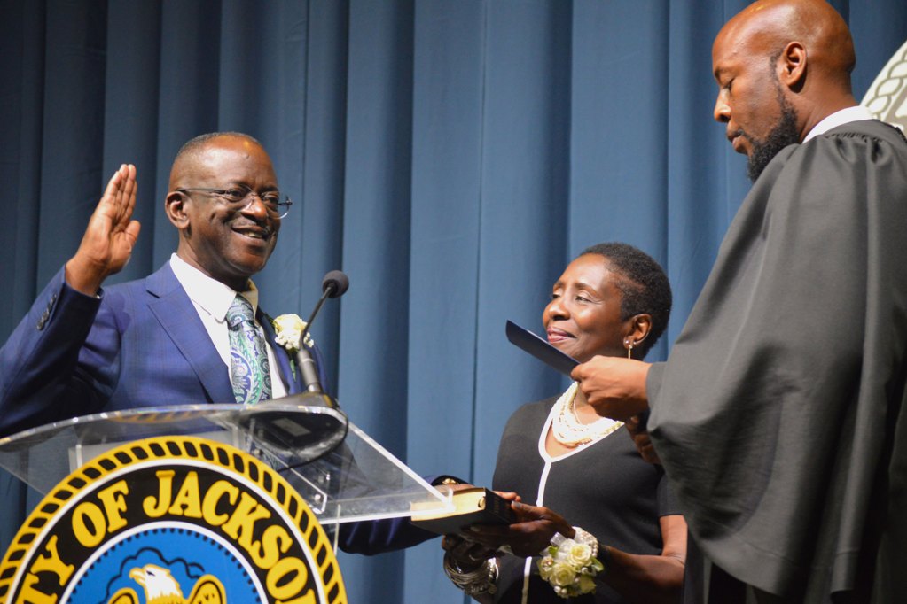 Councilman Vernon Hartley stands with Pamela Junior while being sworn in by judge wearing a black robe