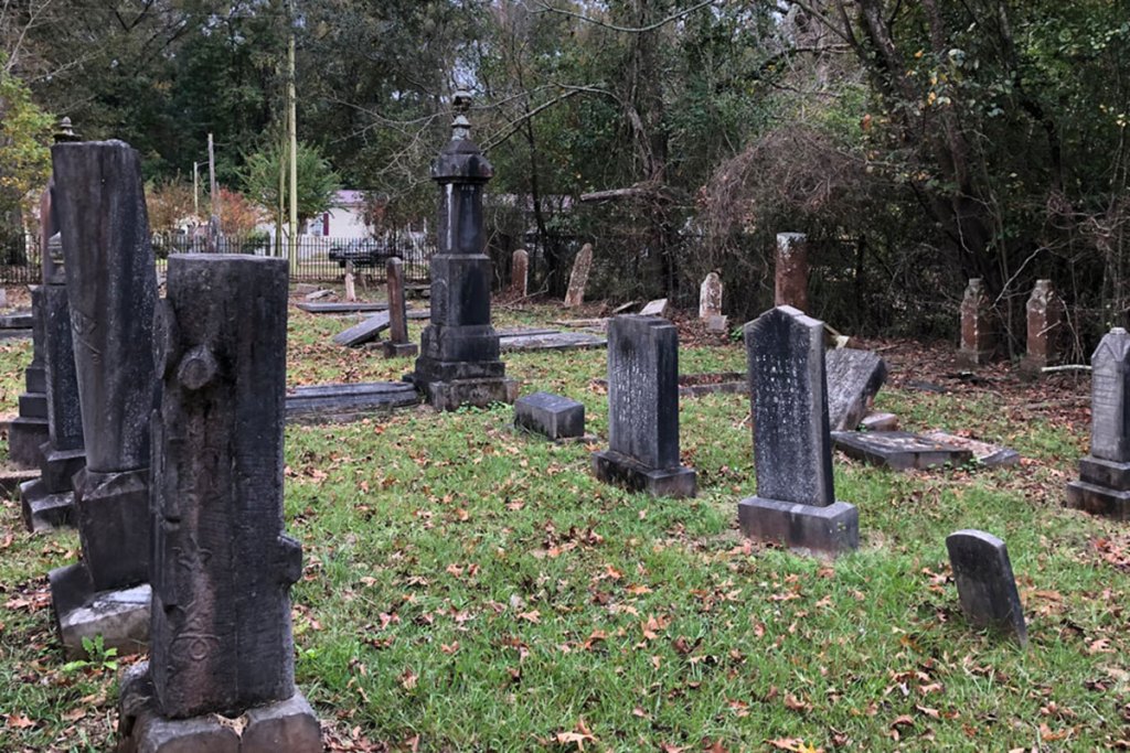 A cemetery with rows of dark weathered headstones