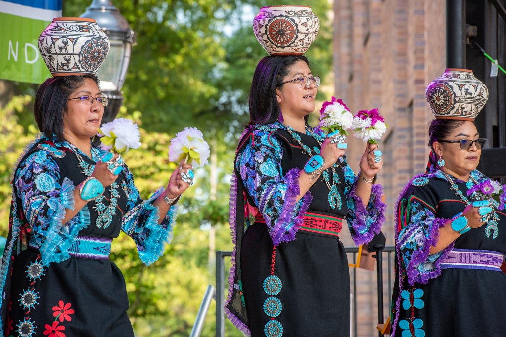 Women dressed in festive attire have the colors of blue, black, and red.
