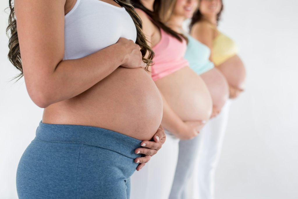 row of pregnant womens' torsos, no visible faces.