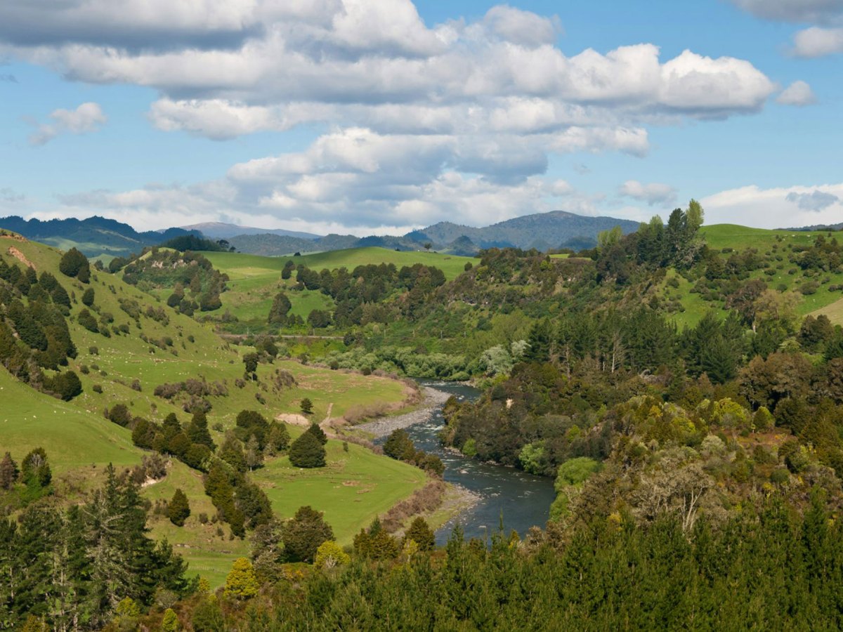 A high view of a valley with a river running through the center, and mountains in the distance