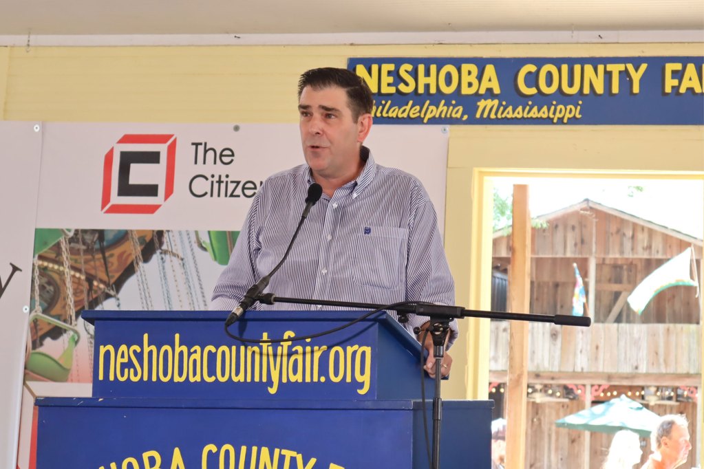Andy Gipson stands behind a podium and speaks into a microphone at the Neshoba County Fair