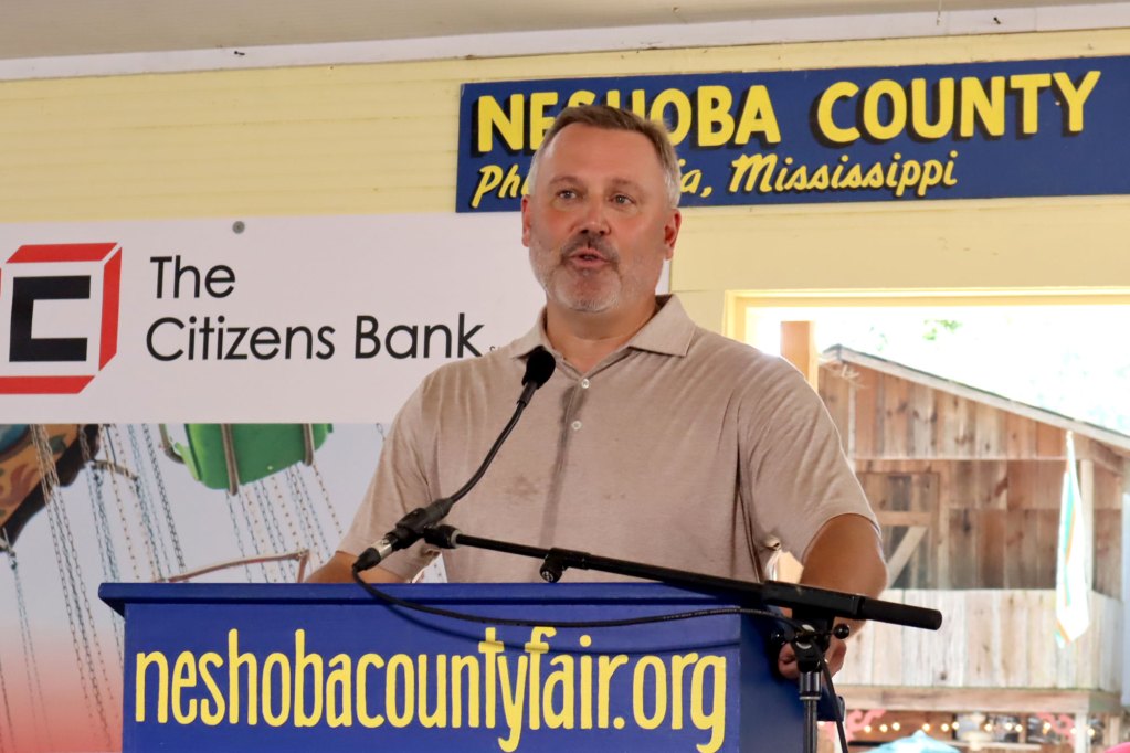 Jason White stands behind a podium and speaks into a microphone at the Neshoba County Fair.