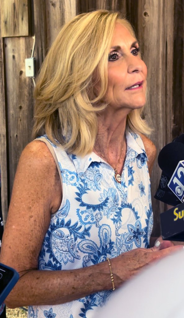 Lynn Fitch speaks into several microphones