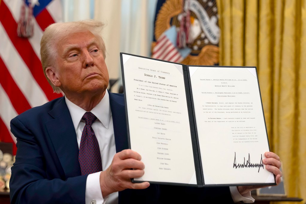 Donald Trump holds up a photo showing a folder with a signed law