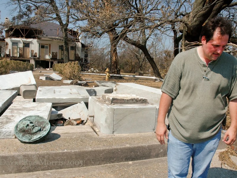 a man looking down in front of a battered building, with an emblem of jefferson davis lying on the ground