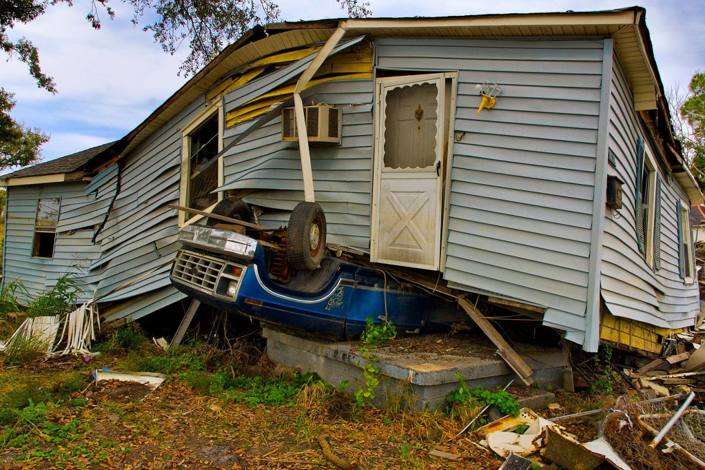 Post hurricane damage that resulted into a house landing on top of an upside down blue truck