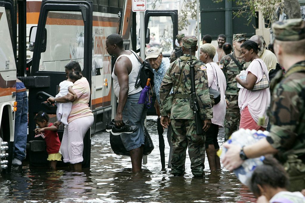 People of all ages, including young children, stand in line to board a bus