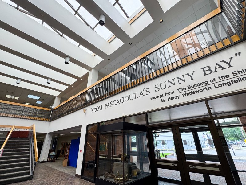 A two story interior of a library with a sign that reads 'From Pascagoula's Sunny Bay' on the wall