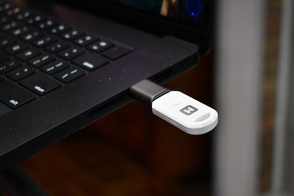 Close-up of a black and white USB device plugged into a black laptop.