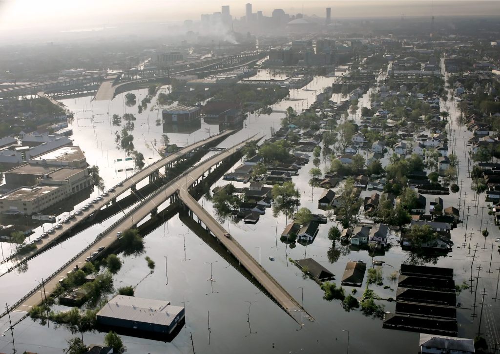 An overhead shot of the flooded streets and homes of New Orleans after Hurricane Katrina, smoke rising on the skyline