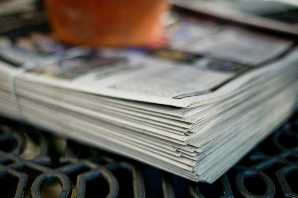 A bundles stack of newspapers sits on a metal table
