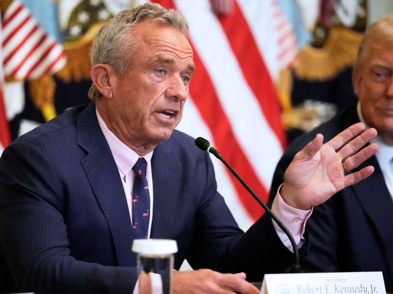 Robert F. Kennedy Jr. speaking at a press conference, with Donald Trump beside him