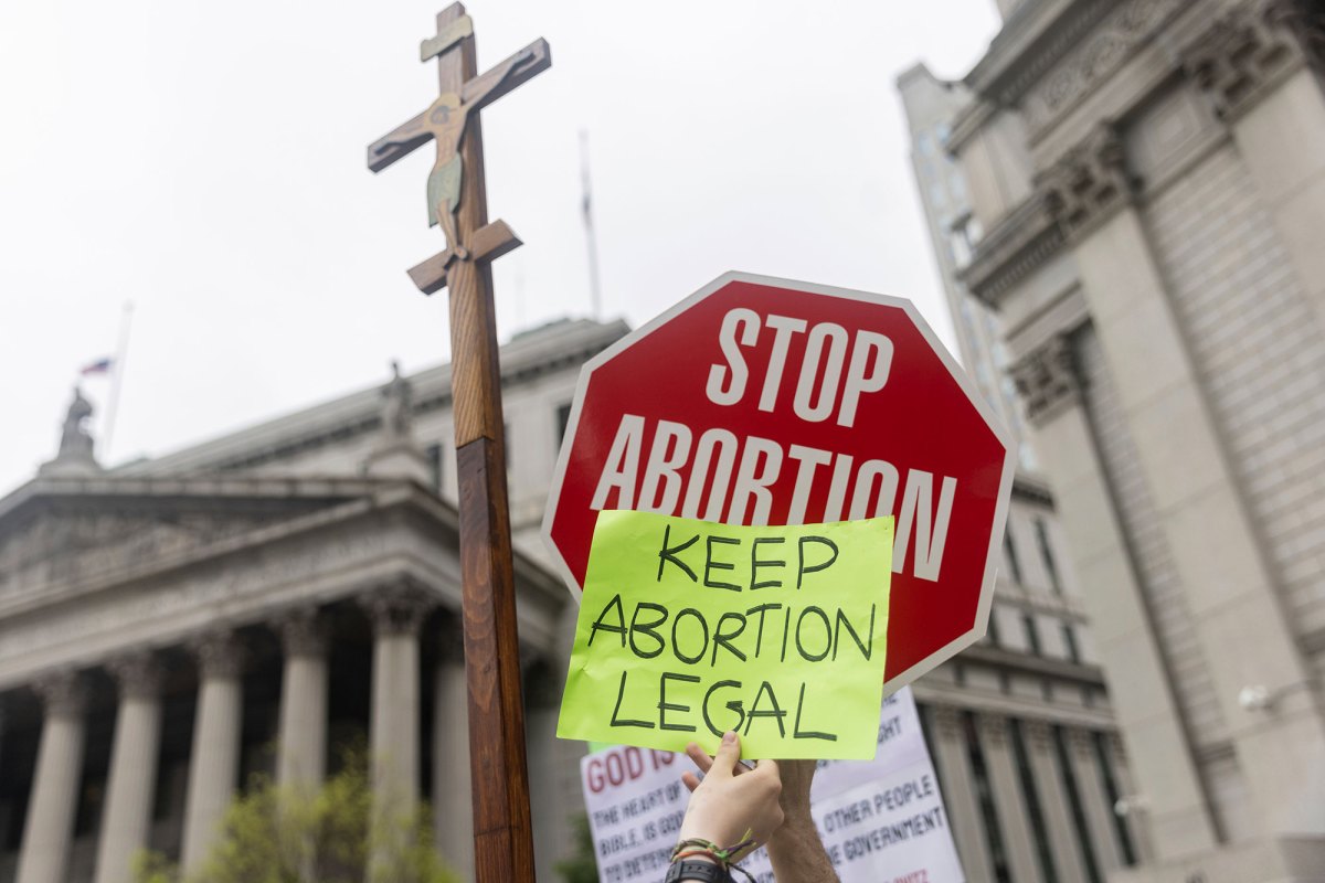 A red stop sign that reads STOP ABORTION is overlayed with a smaller sign that says KEEP ABORTION LEGAL
