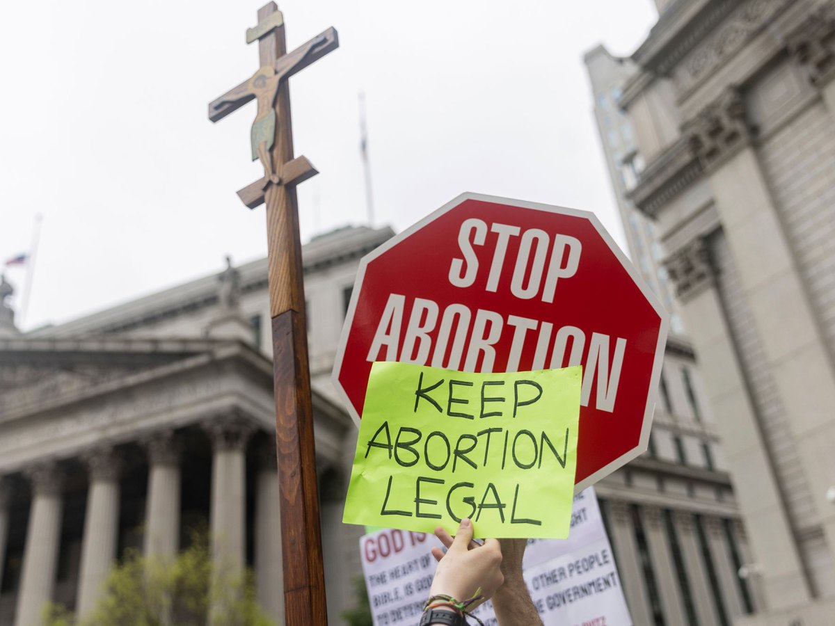 A red stop sign that reads STOP ABORTION is overlayed with a smaller sign that says KEEP ABORTION LEGAL