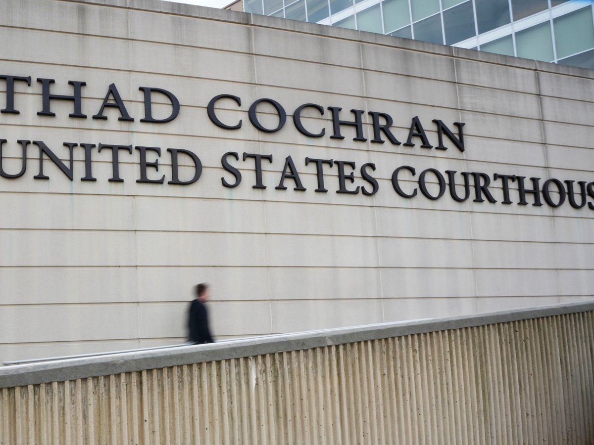 A person walks up a ramp by a wall with a sign that reads Thad Cochran United States Courthouse