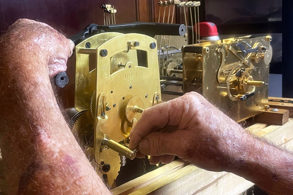 A closeup of hands working on the mechanics of a clock
