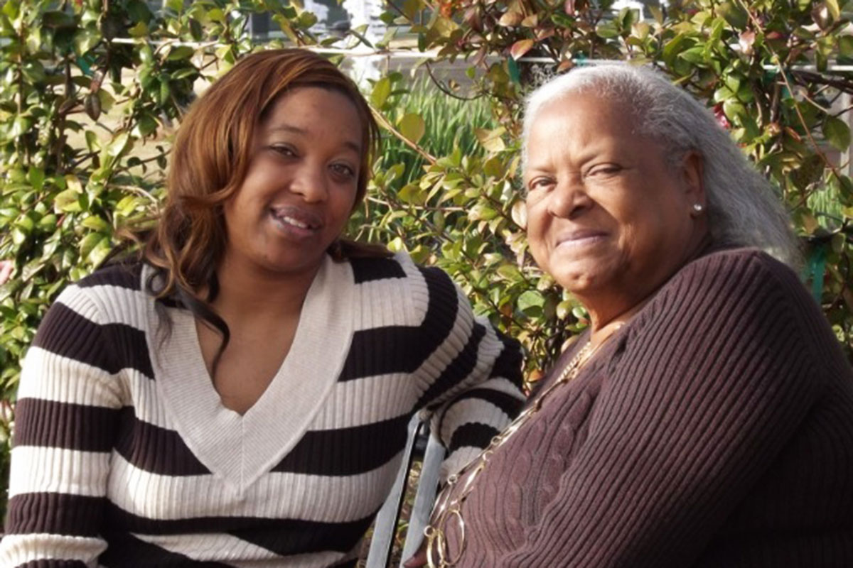 A woman and her daughter sit together on a bench outside
