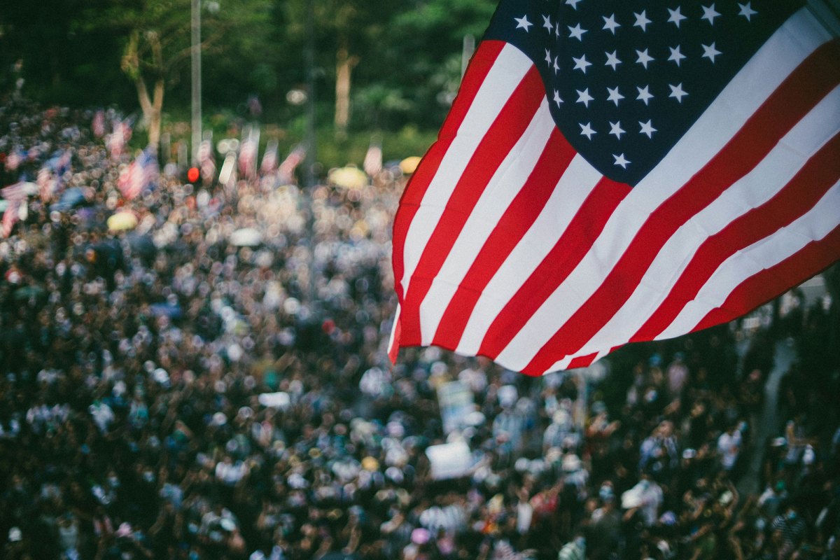 A US flag seen waving outside over a blurry crowd of people
