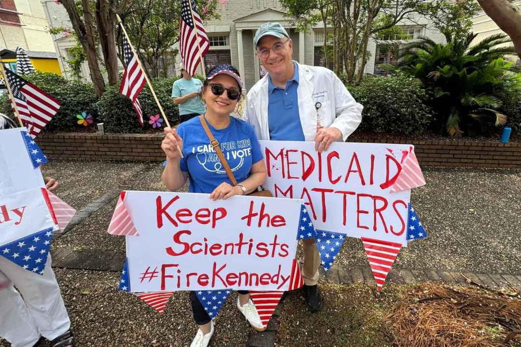 Protesters hold signs that read "Keep the scientists #FireKennedy" and "Medicaid Matters"