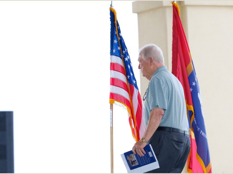 Haley Barbour speaks on an outside stage, with the US and Mississippi Flags standing behind him