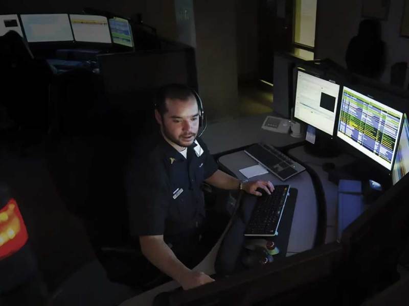 A dispatch person sitting in a call center in front of a bank of monitors