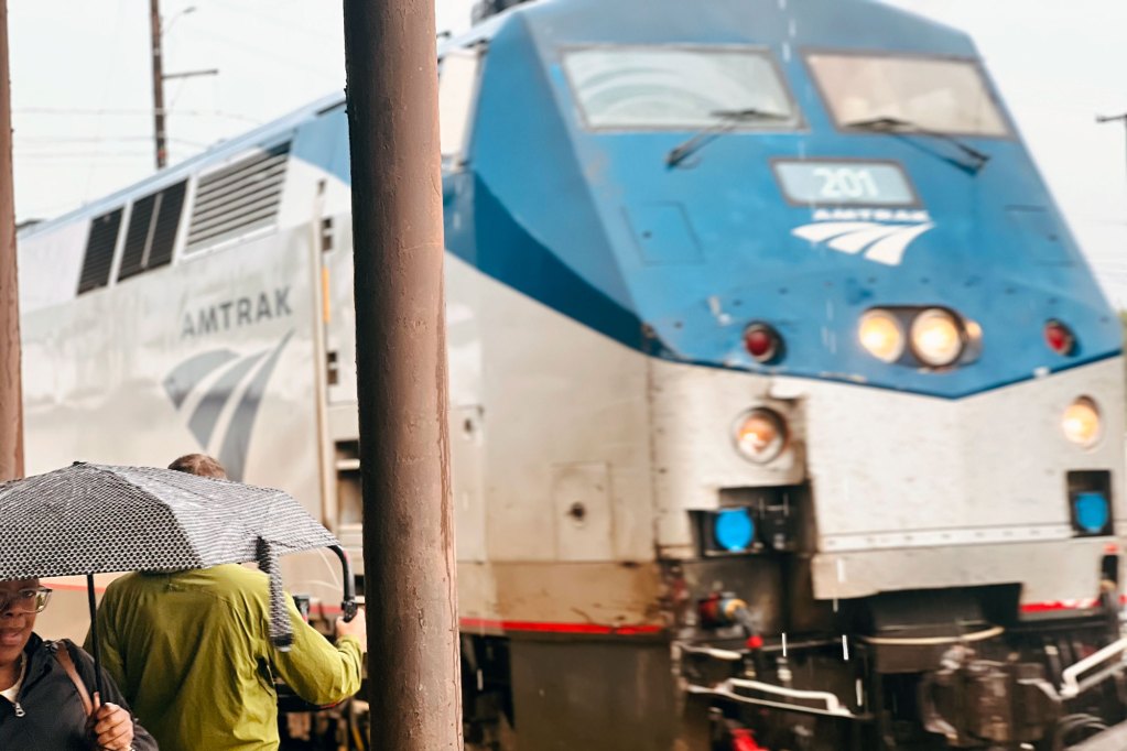 An AMTRAK train stopped at a station on a rainy day