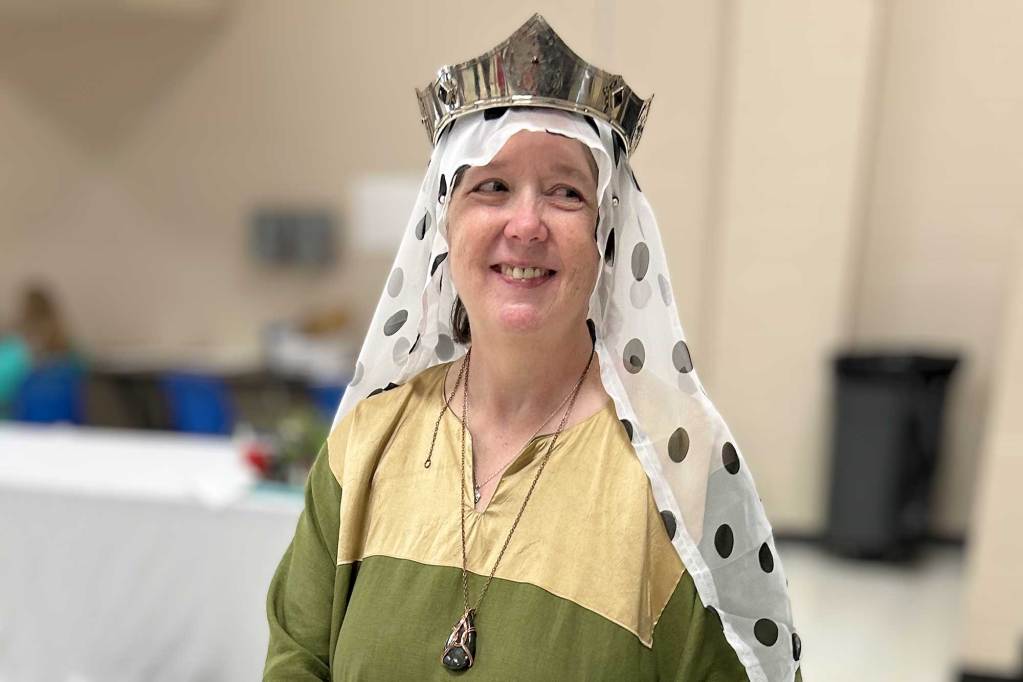 A person wearing a crown over a dotted scarf
