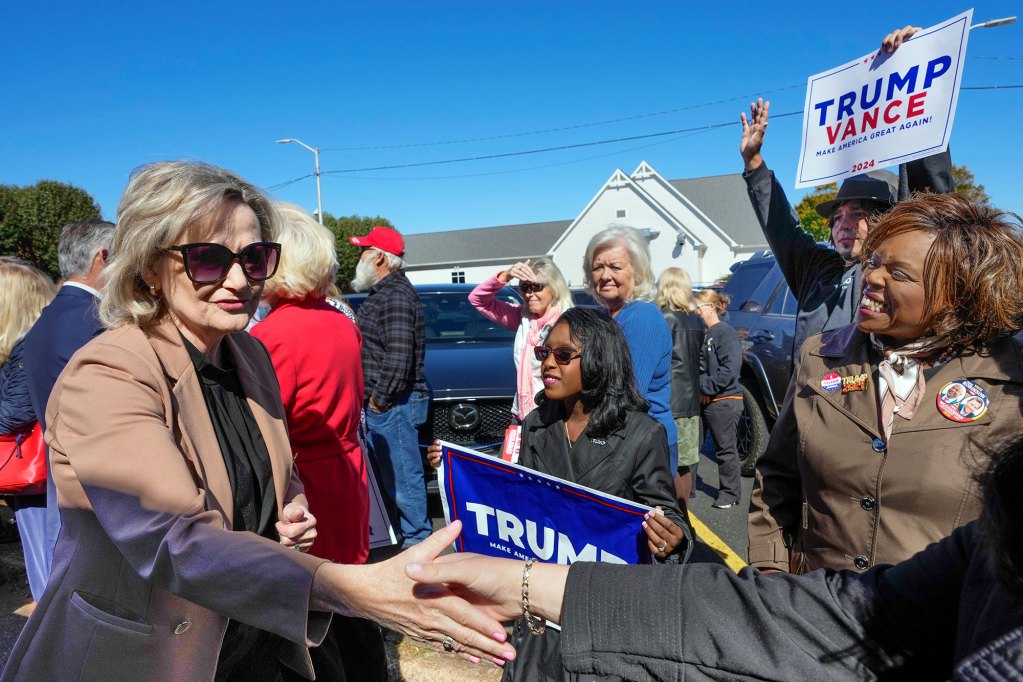 Cindy Hyde-Smith seen shaking hands with supporters carrying Trump Vance signs
