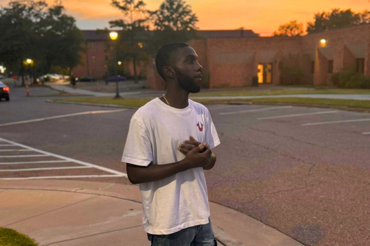 Trey Reed in a white tshirt standing outside on a school campus