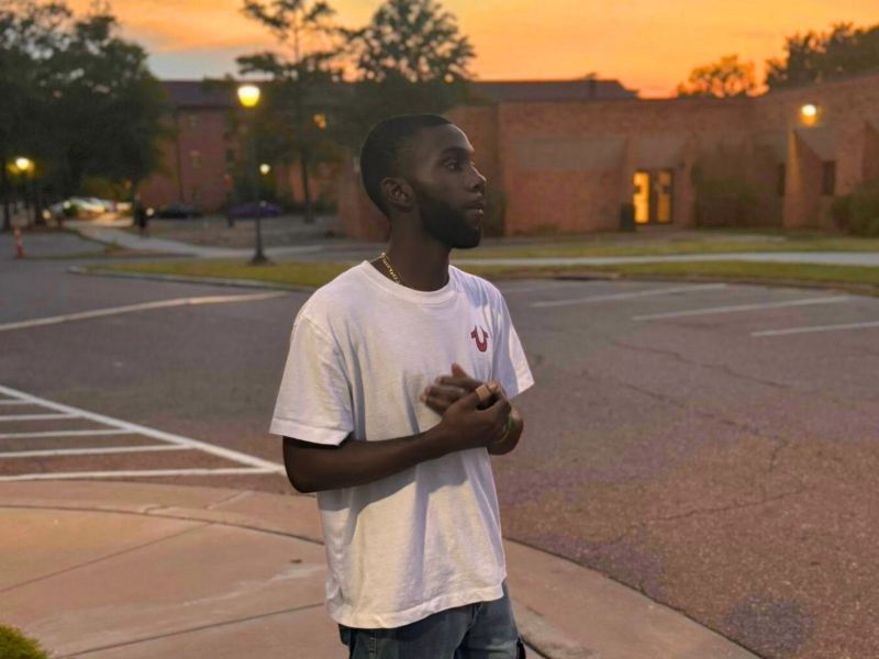 Trey Reed in a white tshirt standing outside on a school campus
