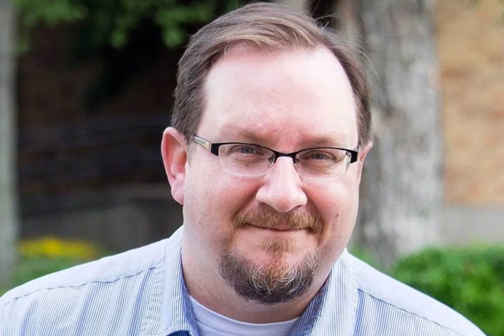 A man wearing glasses standing outside