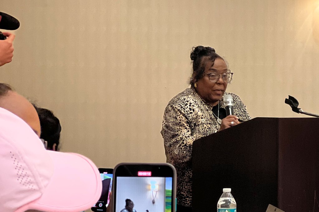 A woman speaks at a podium inside a room