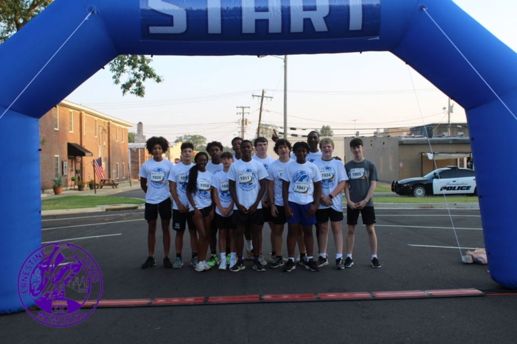 Teens stand below a large blue inflatable start sign