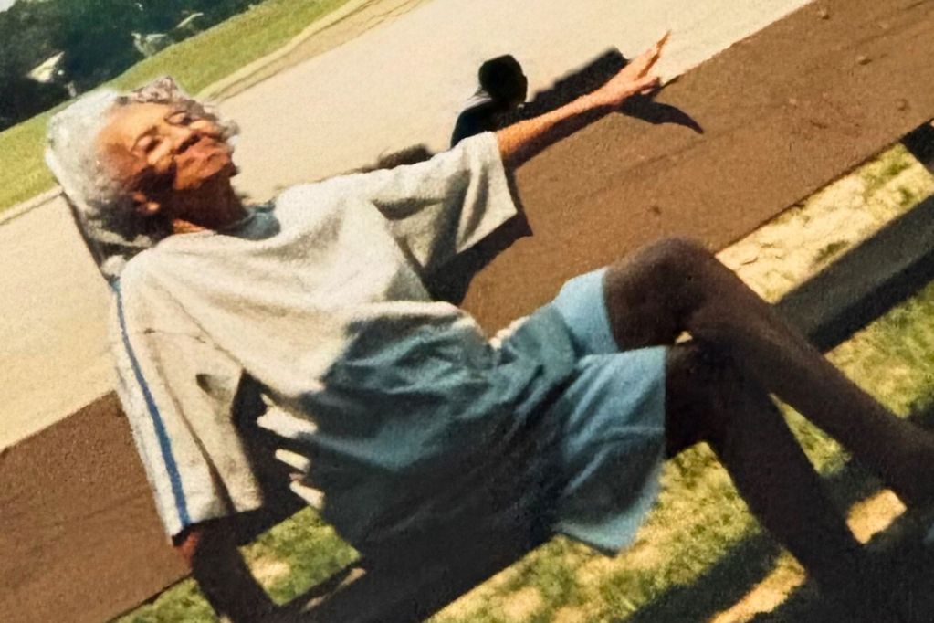 An older woman poses on a a park bench