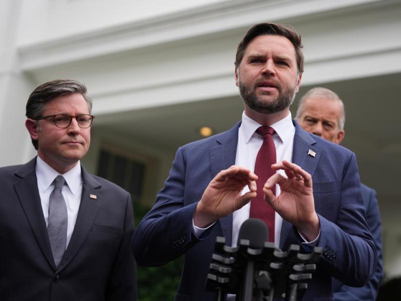 JD Vance speaks at a podium as Mike Johnson listens on